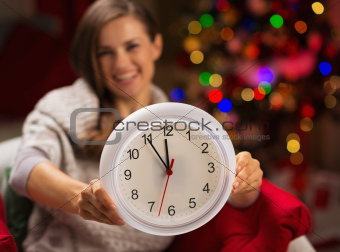 Closeup on clock in hand of happy woman in front of Christmas tree