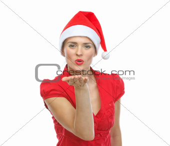 Smiling young woman in Santa hat blowing air kiss