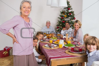 Smiling grandmother standing beside dinner table at christmas