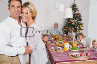 Husband and wife embracing beside the dinner table at christmas