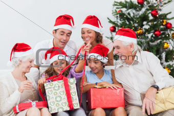 Family watching little girl opening christmas present on the couch