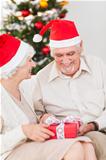 Elderly couple swapping christmas presents on the couch