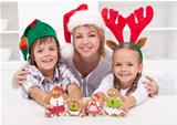 Happy woman with kids in christmas hats holding gingerbread peop