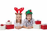 Happy kids with elf and reindeer hats laying among presents