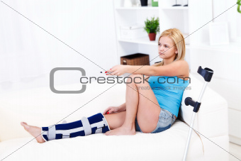 Woman with leg injury holding remote control