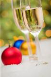 Beautiful Various Colored Christmas Ornaments and Champagne Glasses on Snow Flakes In Front of an Abstract Background.
