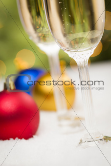 Beautiful Various Colored Christmas Ornaments and Champagne Glasses on Snow Flakes In Front of an Abstract Background.