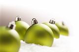 Green Christmas Ornaments on Snow Flakes Over a Grey Background, White at the Top and Right - Great for a Corner Image.