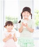 two little girls holding a glass of fresh milk 
