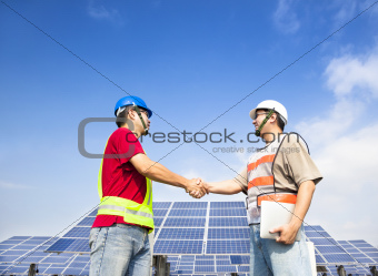  two engineers handshaking  before large solar power station