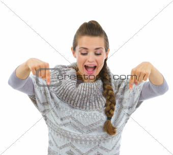 Happy woman in sweater pointing down