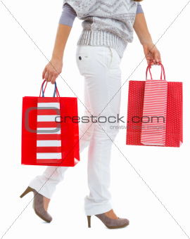 Closeup on woman walking with red shopping bags