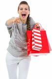 Woman in sweater with shopping bags pointing in camera