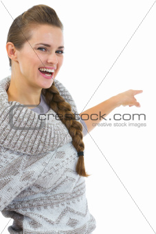 Happy woman in sweater pointing on copy space