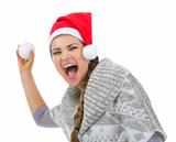 Cheerful woman in Santa hat throwing snowball