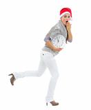 Shocked woman in Santa hat holding clock and running