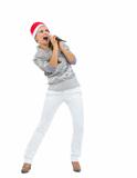 Happy woman in Santa hat singing in microphone and looking on copy space