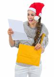 Happy woman in Santa hat reading Christmas letter
