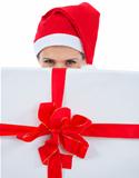 Woman in Santa hat hiding behind huge Christmas present