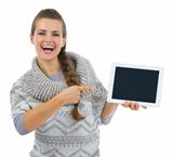 Smiling woman in sweater pointing on tablet PC blank screen
