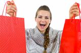 Happy woman in sweater showing red shopping bags