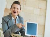 Smiling business woman pointing on tablet PC