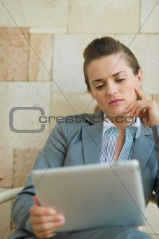 Thoughtful business woman looking in tablet PC