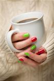 Woman in Sweater with Seasonal Red and Green Nail Polish Holding a Warm Cup of Coffee.
