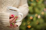 Woman in Sweater with Seasonal Red and Green Nail Polish Holding a Warm Cup of Coffee.