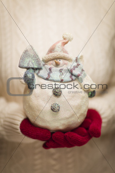 Woman Wearing A Sweater and Seasonal Red Mittens Holding An Ornate Glass Snowman.