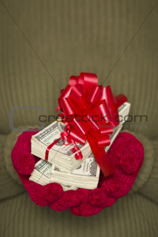 Woman Wearing Red Mittens and Green Sweater Holding Stacks of Hundreds of Dollars of Money with Red Ribbon.