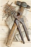 Vintage hammer and pliers with nails on wood background