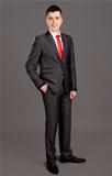 Young businessman standing on grey background