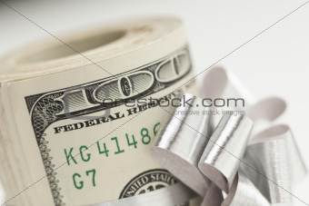 Roll of One Hundred Dollar Bills Tied in a Silver Bow on a White Background.