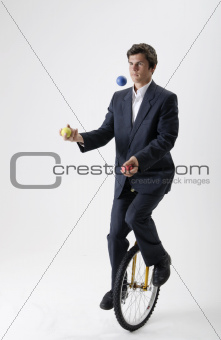 Juggling businessman on unicycle