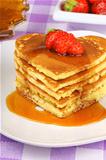 Stack of heart shaped pancakes with syrup and strawberry