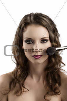 girl getting made-up with brushes, she smiles