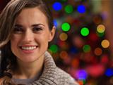 Portrait of happy young woman in front of Christmas lights