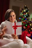 Happy young woman reading Christmas postcard
