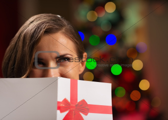 Girl hiding behind Christmas postcard
