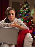 Happy young woman having video chat with lover in front of Christmas tree