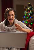 Happy young woman having video chat with family in front of Christmas tree
