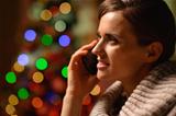 Young woman sitting chair and making phone call in front of Christmas lights