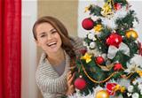 Happy young woman looking out from Christmas tree