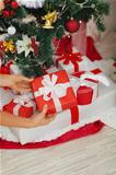 Closeup on woman hands putting Christmas present box under Christmas tree