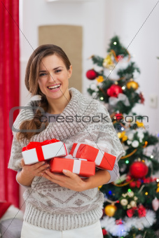 Portrait of smiling woman with present boxes near Christmas tree