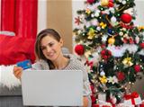 Happy young woman making online purchases near Christmas tree