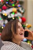 Portrait of smiling woman speaking mobile near Christmas tree