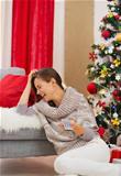 Laughing young woman watching TV near Christmas tree