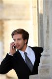 Young businessman on the phone by a stone building